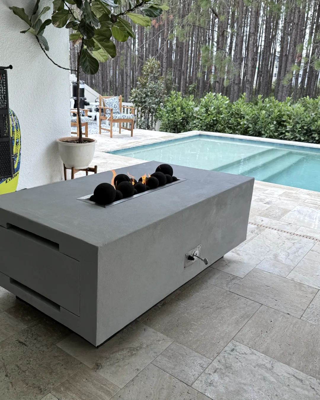 The finished grey concrete fire table lit beside the pool